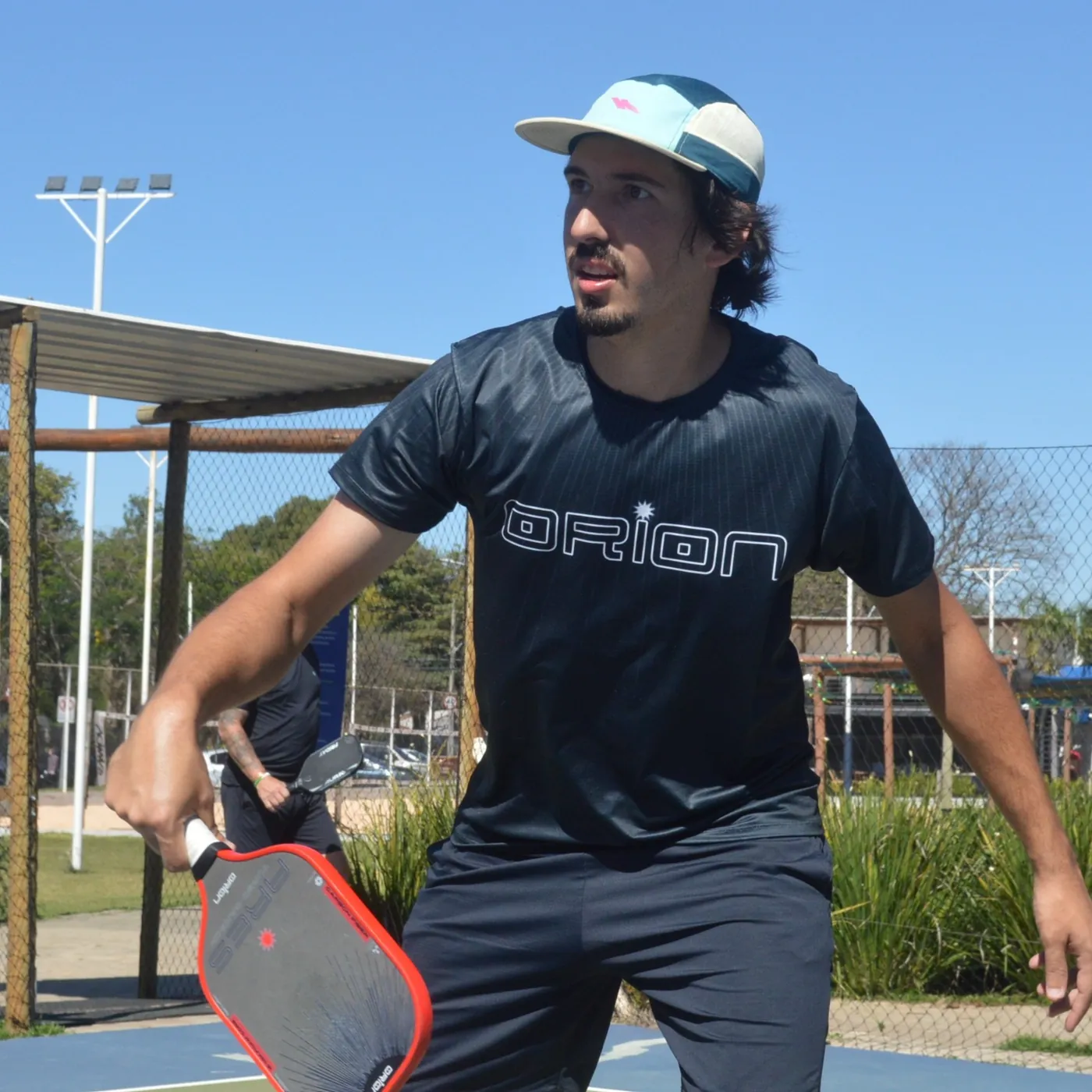 Atleta com camisa Orion jogando com a raquete Orion Ares